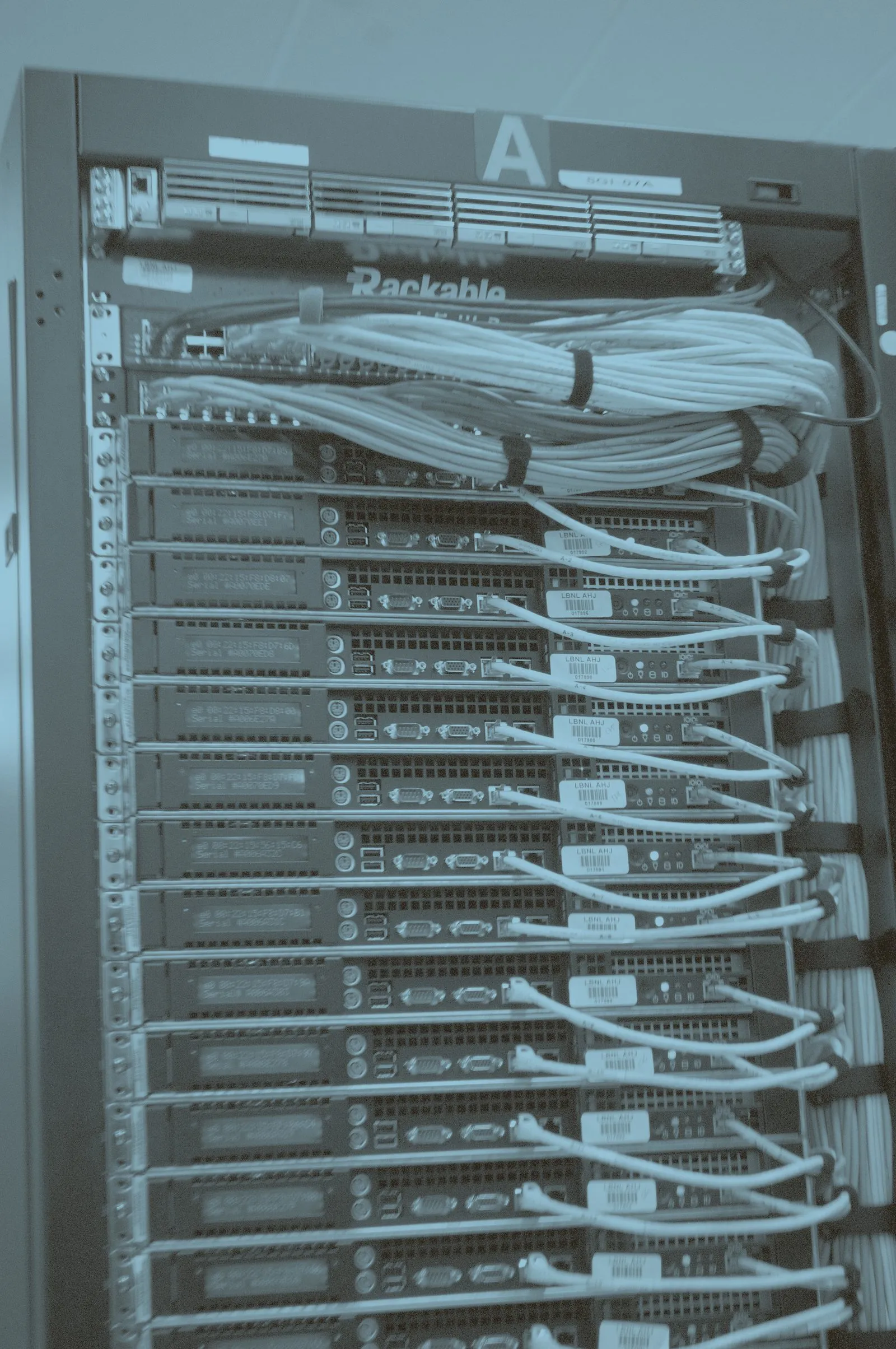 The rear of a server rack, cabling bundled and routed across a column of rack-mounted machines