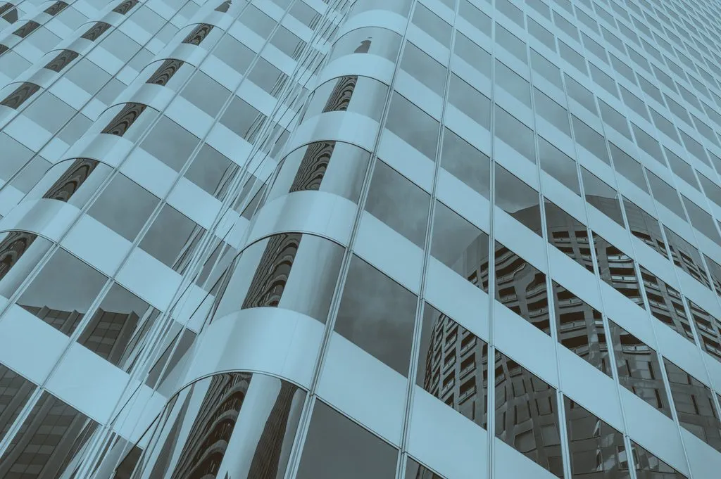 A modern building facade of repeating glass panels seen at an angle