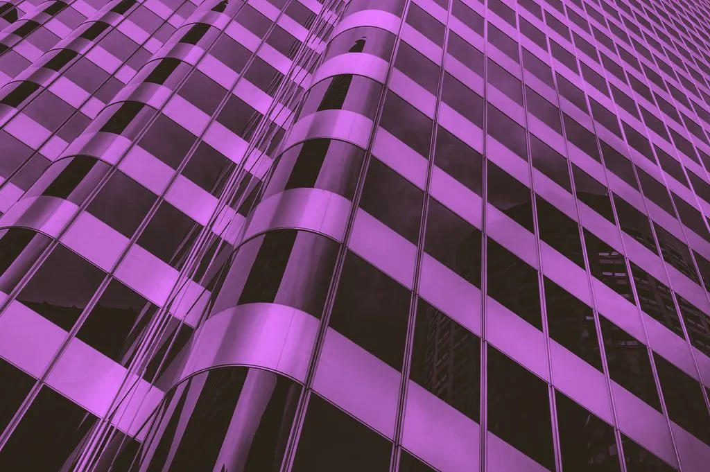 A modern building facade of repeating glass panels seen at an angle